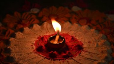 Canlı renklerde güzel rangoli tasarımı. Rangoli 'nin ortasına küçük, aydınlık bir diya ya da yağ lambası konur ve sıcak bir parıltı yayar. renkler şenlikli ve kutlamalı atmosfer. Yavaş çekim videosu. 