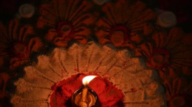 Canlı renklerde güzel rangoli tasarımı. Rangoli 'nin ortasına küçük, aydınlık bir diya ya da yağ lambası konur ve sıcak bir parıltı yayar. renkler şenlikli ve kutlamalı atmosfer. Yavaş çekim videosu. 