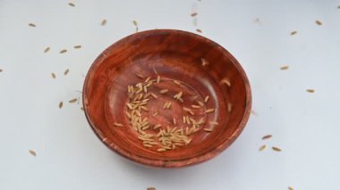 Ahşap kase çeltik dolu. Kahverengi pirinç ya da değirmensiz pirinç deniyor. Pirinç kabuğu çeltik ağacından çıkarılarak üretilir. Çeltik tohumu veya pirinç çekirdeği. Yavaş çekim videosu.