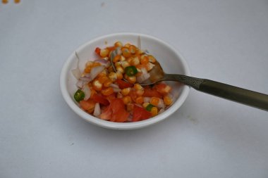 Haşlanmış mısır Chaat. Hint usulü mısır salatası. Tatlı, baharatlı ve keskin. Chaat masala, kavrulmuş kimyon tozu, kırmızı biber tozu, kişniş yaprağı, soğan ve domatesle karıştırılır. Hint yemekleri..