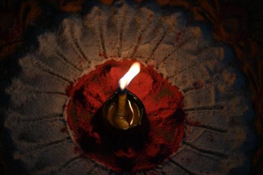 Canlı renklerde güzel rangoli tasarımı. Rangoli 'nin ortasına küçük, aydınlık bir diya ya da yağ lambası konur ve sıcak bir parıltı yayar. renkler şenlikli ve kutlama atmosferi.
