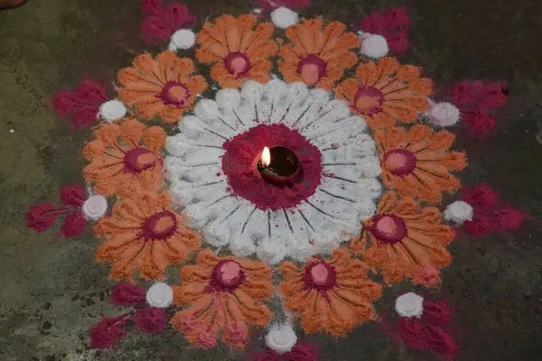 Canlı renklerde güzel rangoli tasarımı. Rangoli 'nin ortasına küçük, aydınlık bir diya ya da yağ lambası konur ve sıcak bir parıltı yayar. renkler şenlikli ve kutlama atmosferi.