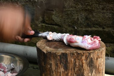 Tahtada keçi eti doğramak. Hint köyündeki geleneksel demir aletlerden taze çiğ ya da pişmemiş koyun eti. Keçi etini küçük parçalara ayırmak..