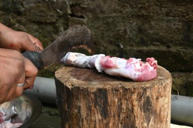 Tahtada keçi eti doğramak. Hint köyündeki geleneksel demir aletlerden taze çiğ ya da pişmemiş koyun eti. Keçi etini küçük parçalara ayırmak..
