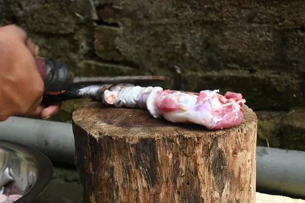 Tahtada keçi eti doğramak. Hint köyündeki geleneksel demir aletlerden taze çiğ ya da pişmemiş koyun eti. Keçi etini küçük parçalara ayırmak..