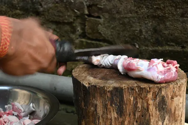 Tahtada keçi eti doğramak. Hint köyündeki geleneksel demir aletlerden taze çiğ ya da pişmemiş koyun eti. Keçi etini küçük parçalara ayırmak..