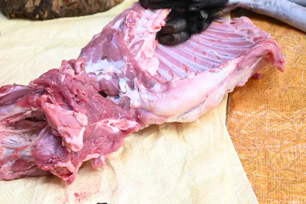 Taze çiğ ya da pişmemiş keçi eti. Geleneksel Hint köyünde koyun kesimi. Keçi etini parçalara ayırmak..