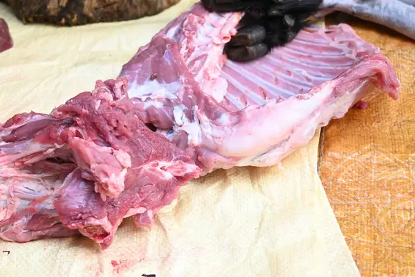 Taze çiğ ya da pişmemiş keçi eti. Geleneksel Hint köyünde koyun kesimi. Keçi etini parçalara ayırmak..