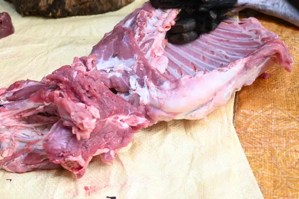 Taze çiğ ya da pişmemiş keçi eti. Geleneksel Hint köyünde koyun kesimi. Keçi etini parçalara ayırmak..