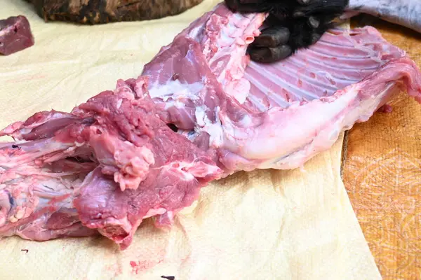 Taze çiğ ya da pişmemiş keçi eti. Geleneksel Hint köyünde koyun kesimi. Keçi etini parçalara ayırmak..