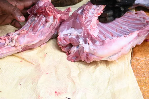 Taze çiğ ya da pişmemiş keçi eti. Geleneksel Hint köyünde koyun kesimi. Keçi etini parçalara ayırmak..