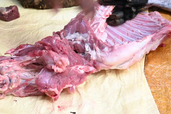 Taze çiğ ya da pişmemiş keçi eti. Geleneksel Hint köyünde koyun kesimi. Keçi etini parçalara ayırmak..