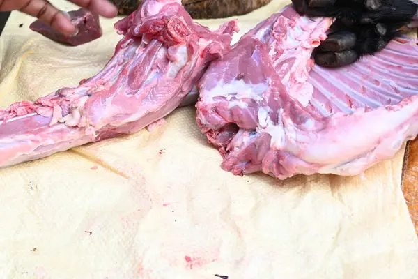 Taze çiğ ya da pişmemiş keçi eti. Geleneksel Hint köyünde koyun kesimi. Keçi etini parçalara ayırmak..