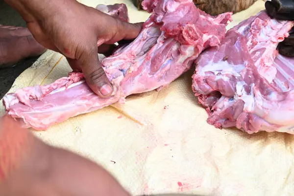 Taze çiğ ya da pişmemiş keçi eti. Geleneksel Hint köyünde koyun kesimi. Keçi etini parçalara ayırmak..