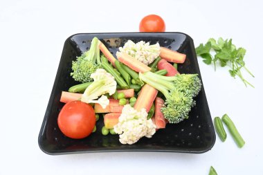 Canlı taze sebze karışımı. İçinde brokoli, karnabahar, domates, havuç, yeşil fasulye ve bezelye var. Bahar mevsiminin renkli sebzeleri, sağlık için iyidir. Renkli ekran.