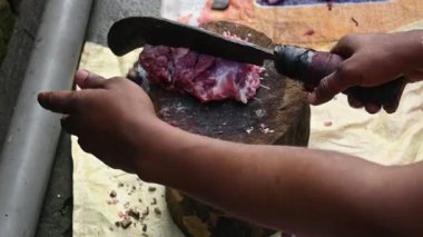 Keçi eti doğrama. Hint köyündeki geleneksel demir aletlerden taze çiğ ya da pişmemiş koyun eti. Keçi etini küçük parçalara ayırmak. Yavaş çekim videosu. 