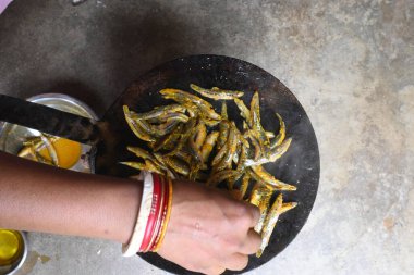 Small Snakehead or Channa orientalis Fish being fried in a pan. Fish are typically marinated with spices like turmeric, salt, and chili powder before being deep fried until they are crispy and golden.