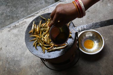 Small Snakehead or Channa orientalis Fish being fried in a pan. Fish are typically marinated with spices like turmeric, salt, and chili powder before being deep fried until they are crispy and golden.