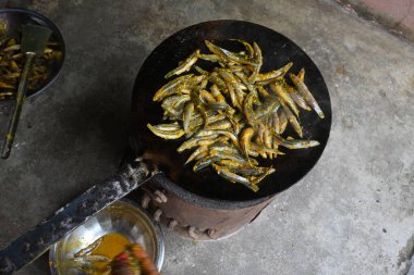 Small Snakehead or Channa orientalis Fish being fried in a pan. Fish are typically marinated with spices like turmeric, salt, and chili powder before being deep fried until they are crispy and golden.