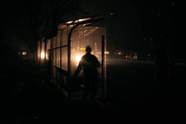 Otobüsteki adamlar karanlıkta, farların önünde dururlar. Karartma konsepti.