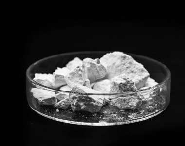 Kalsiyum klorür taneleri, katı halde tuz soğutma makinelerinde, yol tozlarında ve buzlarda peynir ve çimentoda kullanılır. Endüstriyel kullanım, izole edilmiş siyah arkaplan, telif alanı