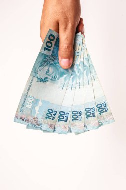 Brezilya 'dan 100 reais banknot, izole edilmiş beyaz arka planda erkek eliyle tutulmuş. Brezilya 'dan 100 reais' in banknotları, ödeme günü..