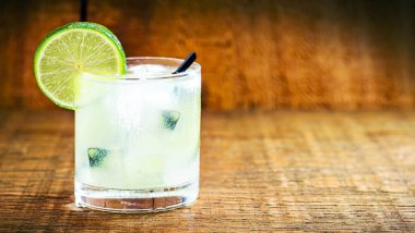 Brazilian caipirinha, cachaca drink with fruits, on wooden background. Lemon flavor, with copy space