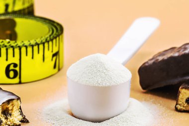 Kaşık dolusu kreatin ya da kazein dozunu ölçmek ve mezuranın, telif alanının, diyet takviyesi konseptinin, makrofotoğrafçılığın yanındaki protein çikolatalarını ölçmek