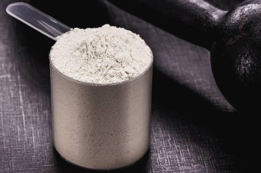 Kaşık ölçmede kazein, ağırlık ve ağırlık eğitimli siyah arkaplan, makrofotoğrafçılık.