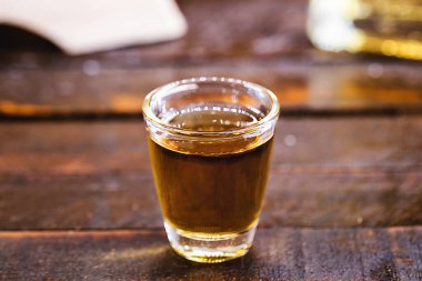 Glass of golden rum, with bottle. Bottle pouring alcohol into a small glass. Brazilian export type drink. Brazilian product for export, distilled drink known as brandy or pinga. Day of cachaca.