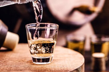 Glass of golden rum, with bottle. Bottle pouring alcohol into a small glass. Brazilian export type drink. Brazilian product for export, distilled drink known as brandy or pinga. Day of cachaca.
