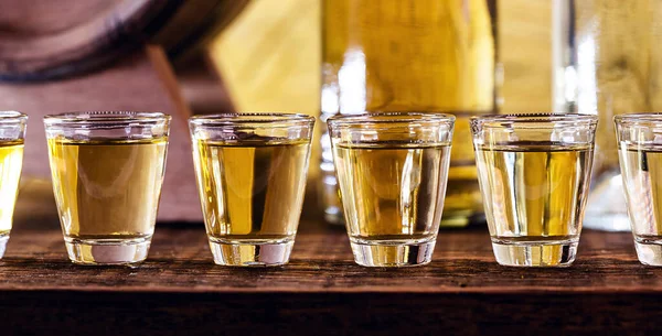 stock image Glass of golden rum, with bottle. Bottle pouring alcohol into a small glass. Brazilian export type drink. Brazilian product for export, distilled drink known as brandy or pinga. Day of cachaca.