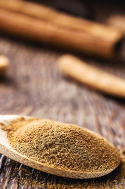 Kırsal ahşap arka planda bir kaşık tarçın. Organik mutfak malzemesi..