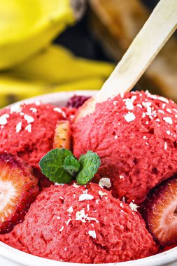 Arka planda tropikal meyveli vegan çilekli dondurma, çilek, muz, avokado ve jabuticaba.