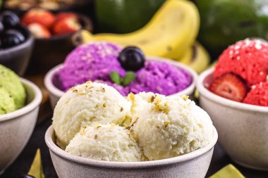 Arkaplanda tropikal meyveler, çilek, muz, jabuticaba ve avokado aromalı organik meyvelerden yapılmış vejetaryen dondurması.