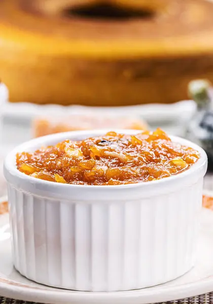 pot with homemade pumpkin jam, typical Brazilian dessert at the June and July parties, in the background fuba cake and candied sweets