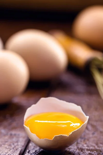 broken country chicken egg, visible yolk on wooden table, cooking with organic eggs