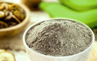 Ev yapımı yeşil muz unu, arka planda meyve ve kızarmış muz cipsi ve dilimler var.