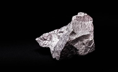 İzole edilmiş siyah zemin üzerinde ham çinko külçesi, alaşım ve çelik üretiminde kullanılan metal.