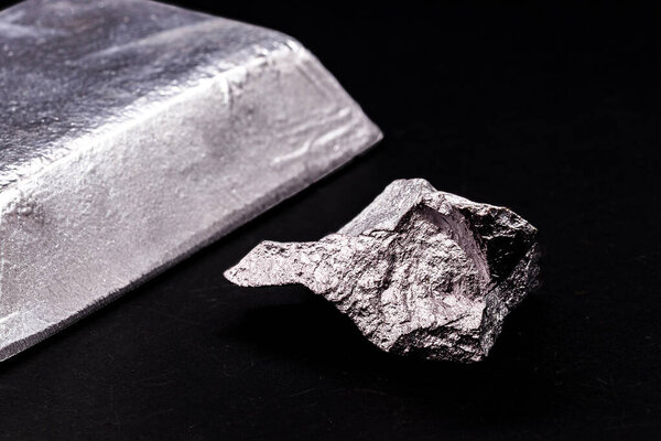 aluminum ingot or bar next to aluminum ore, recycling or metal industry concept