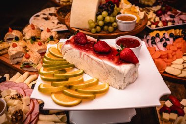 Ekmek, çilek, peynir ve sosis ile süslenmiş açık büfe masasında servis edilen çilekli dondurmalı pasta, açık büfedeki tipik Brezilya tatlıları.