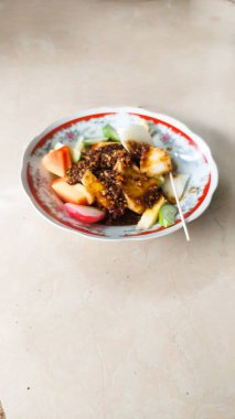 Rujak, tatlı ve baharatlı taze meyve karışımıdır. Tabakta servis edilir.