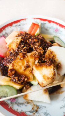 Rujak, tatlı ve baharatlı taze meyve karışımıdır. Tabakta servis edilir.