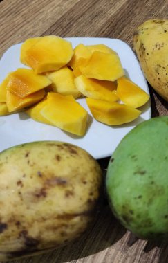 Taze sarı mango ağaçları, dayanıklılık ve sağlığı korumak için bol miktarda C vitamini içerir. Beyaz bir tabakta servis edilir..