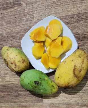 Taze sarı mango ağaçları, dayanıklılık ve sağlığı korumak için bol miktarda C vitamini içerir. Beyaz bir tabakta servis edilir..
