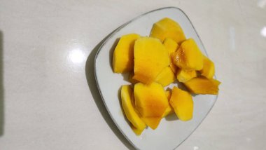 Taze sarı mango ağaçları, dayanıklılık ve sağlığı korumak için bol miktarda C vitamini içerir. Beyaz bir tabakta servis edilir..