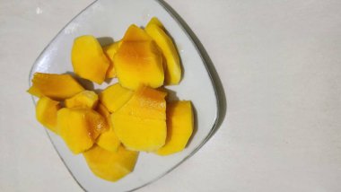 Taze sarı mango ağaçları, dayanıklılık ve sağlığı korumak için bol miktarda C vitamini içerir. Beyaz bir tabakta servis edilir..