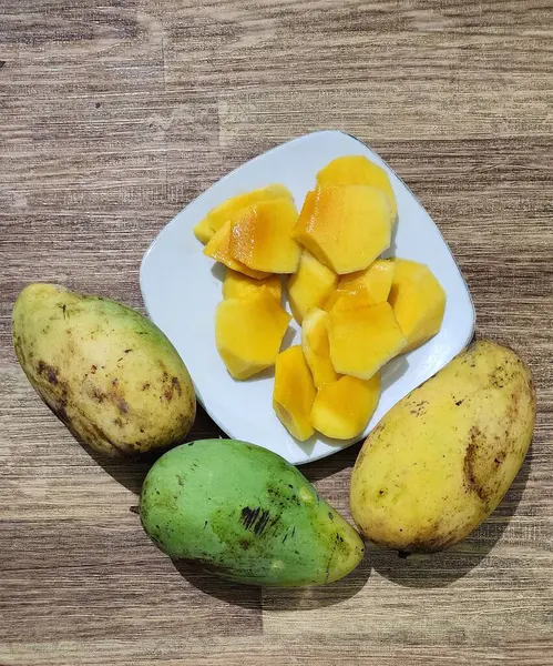Taze sarı mango ağaçları, dayanıklılık ve sağlığı korumak için bol miktarda C vitamini içerir. Beyaz bir tabakta servis edilir..
