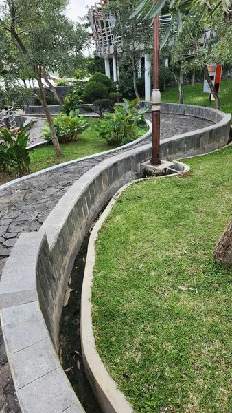 Bir bahçe yolu dolambaçlı bir tasarım, düzgün doğal taştan yapılmış serin yeşil bitkiler