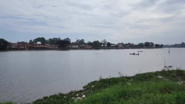 Sabah bulutlu bir gökyüzünde Sipin gölünü geçen bir tekne.